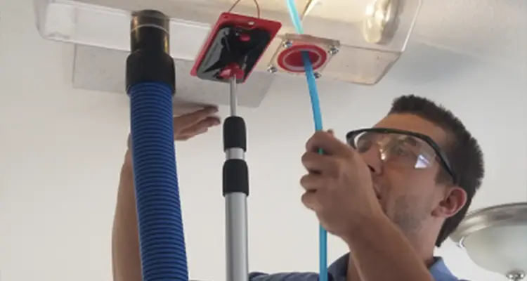 Man cleaning an overhead air duct